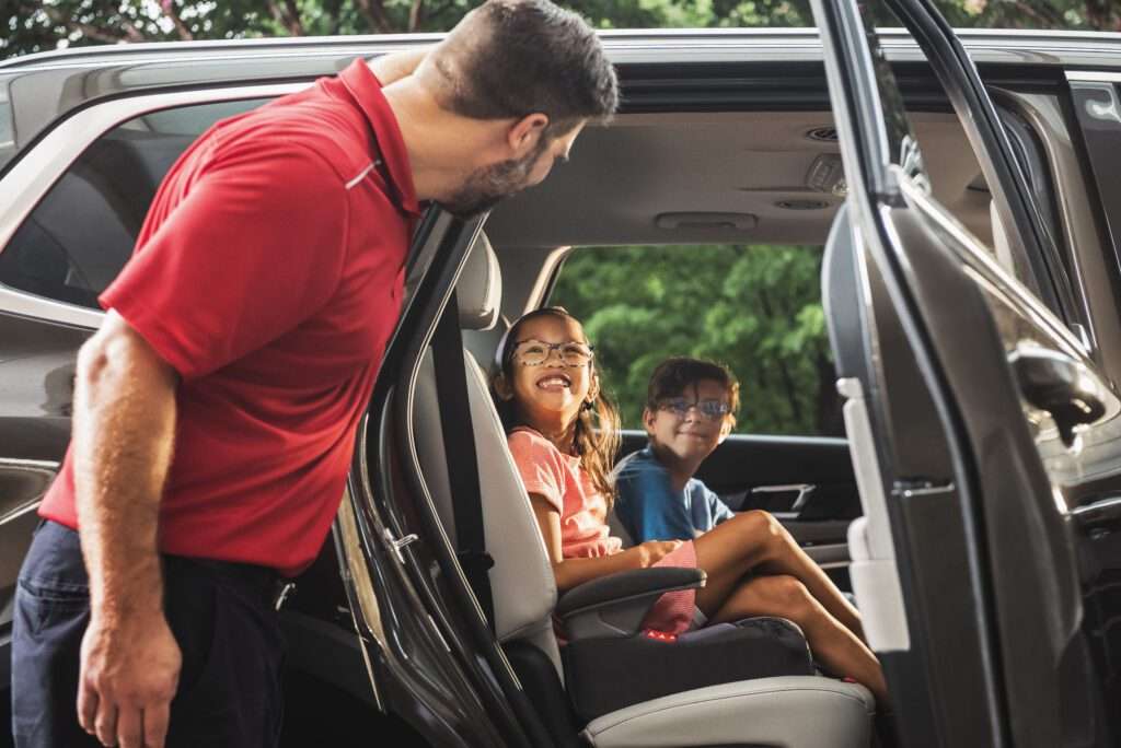 SP+ valet employee smiling at kids in car