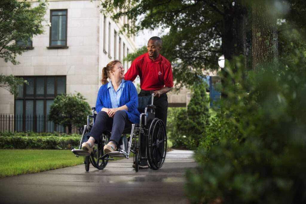 Employé SP+ poussant un invité en fauteuil roulant