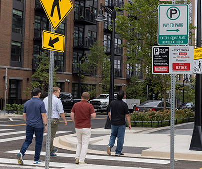 Personnes traversant la route à un passage piéton entouré de panneaux de stationnement